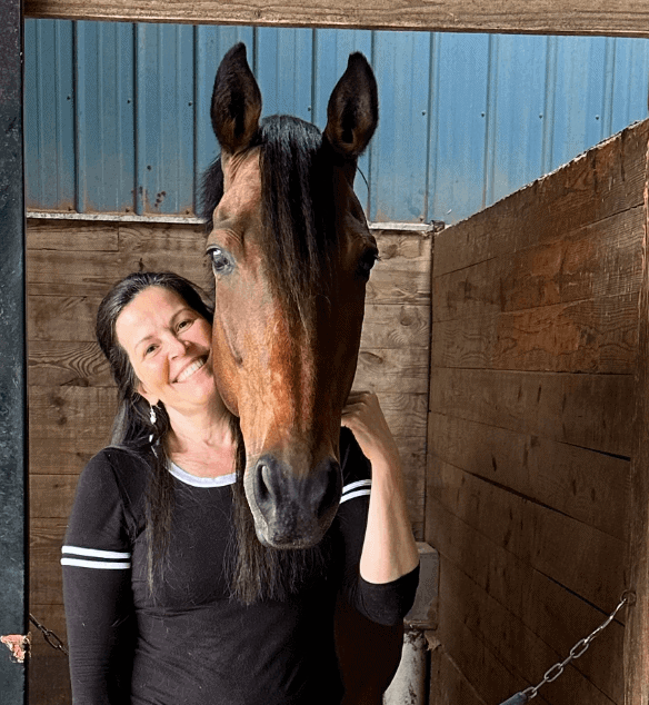 Horse and woman sharing a joyful moment in a stable setting.
